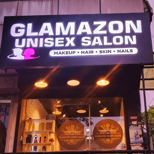 The illuminated shopfront sign for Glamazon Unisex Salon, reading "Makeup · Hair · Skin · Nails", above a lit entrance with shelving visible inside.